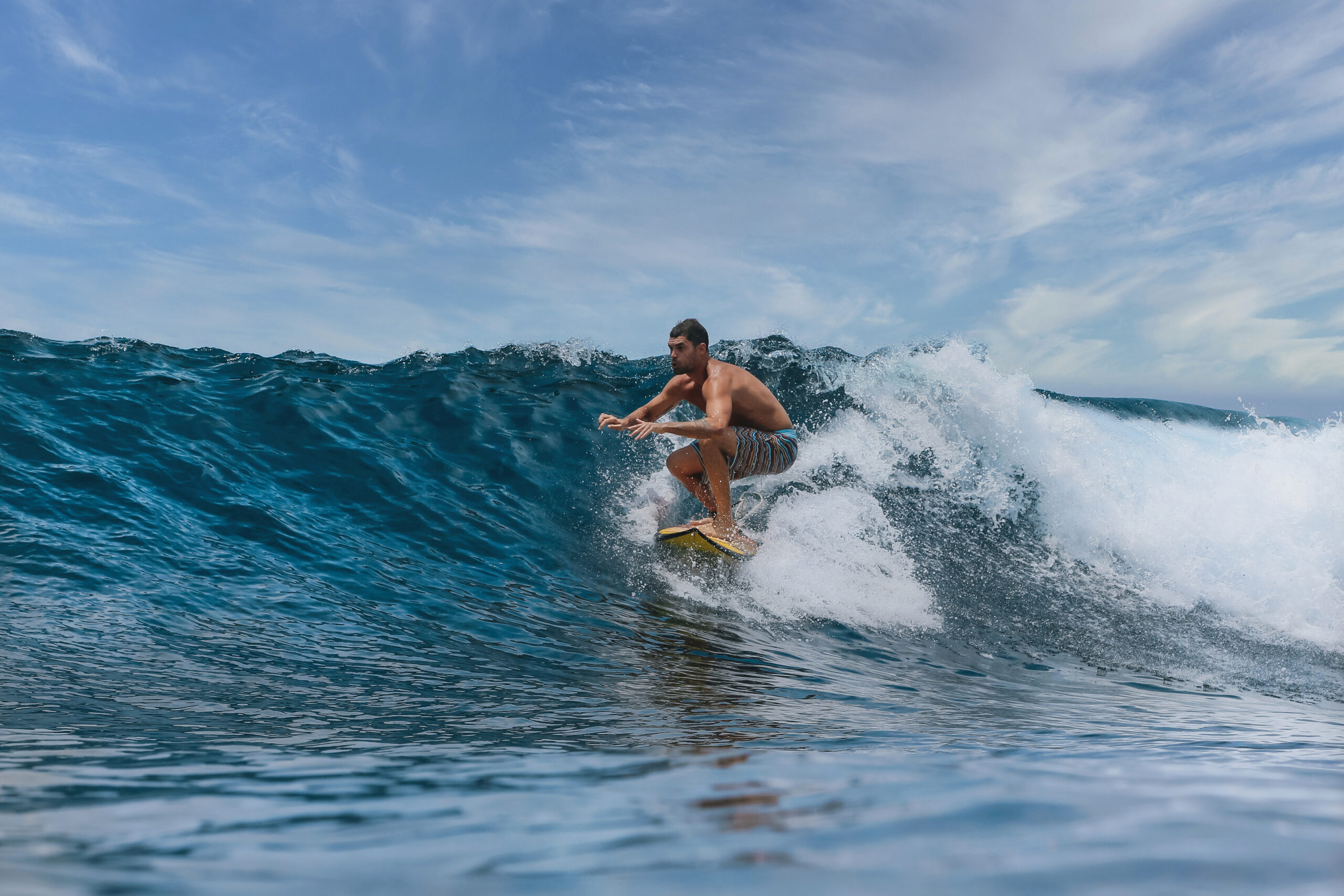 Male surfer on a blue wave at Bali island